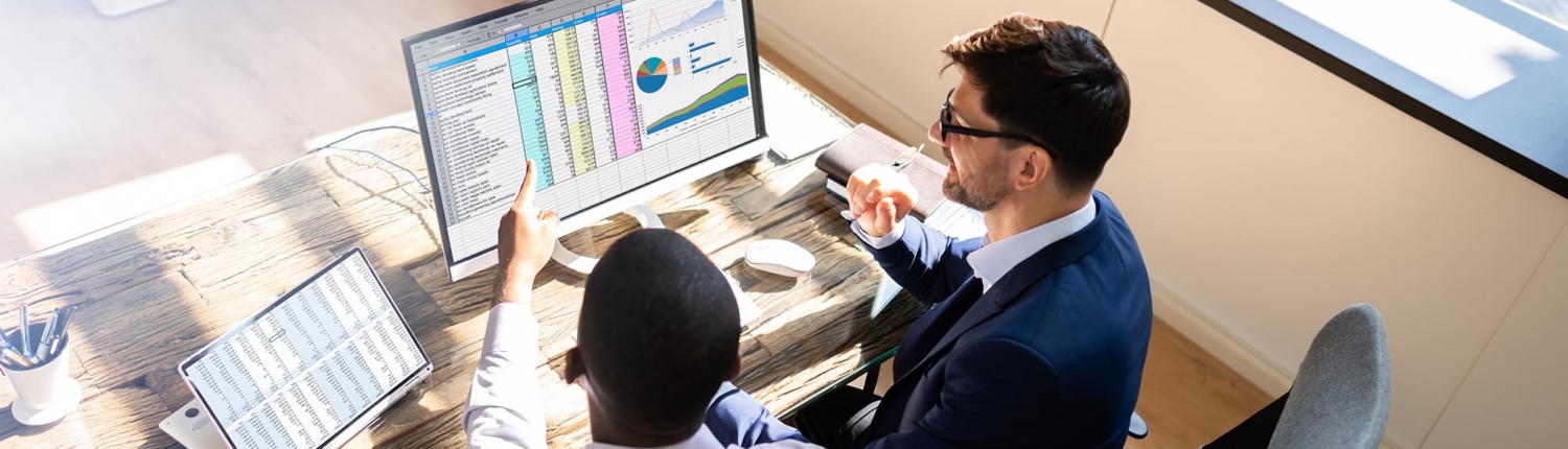 Image of two business people reviewing billing information on a computer.