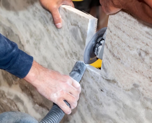 Artisan cuts edges in marble kitchen countertop with hand circular saw