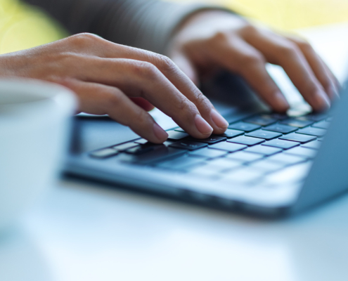 Side view of a pair of hands typing on keyboard