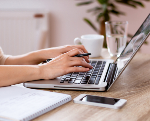 Side view of hands typing on laptop keyboard