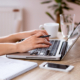 Side view of hands typing on laptop keyboard