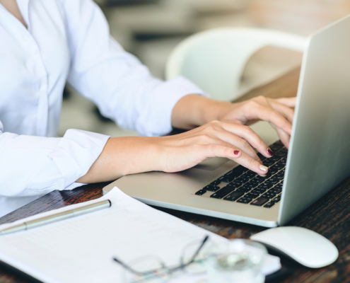 Cropped shot of businesswoman using laptop computer while sitting at desk