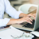 Cropped shot of businesswoman using laptop computer while sitting at desk