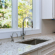 Side view of a sink in clean kitchen, marble countertops