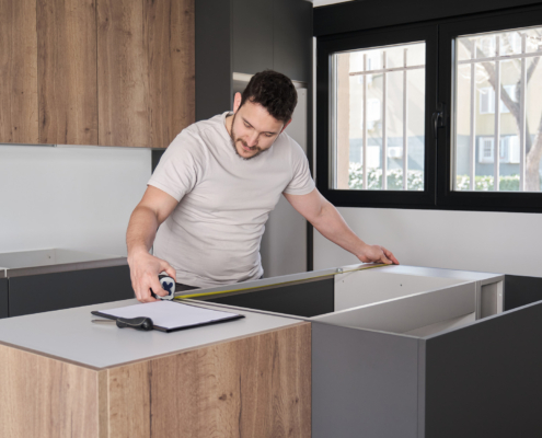 man using measuring tape before placing countertops on modern kitchen